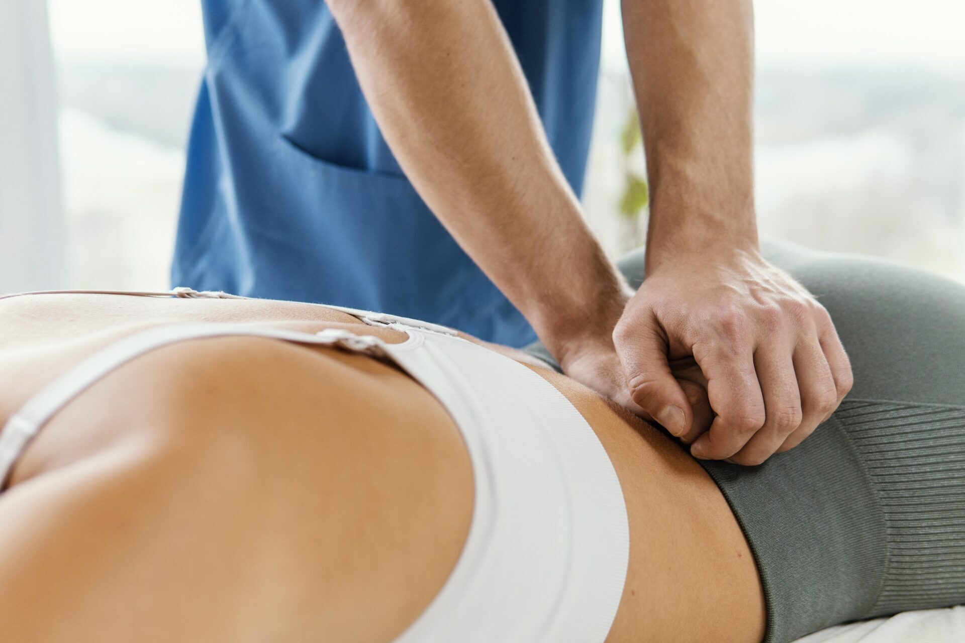 Terapeuta uciskający kręgosłup pacjentki, która leży na brzuchu w trakcie chiropraktyki.